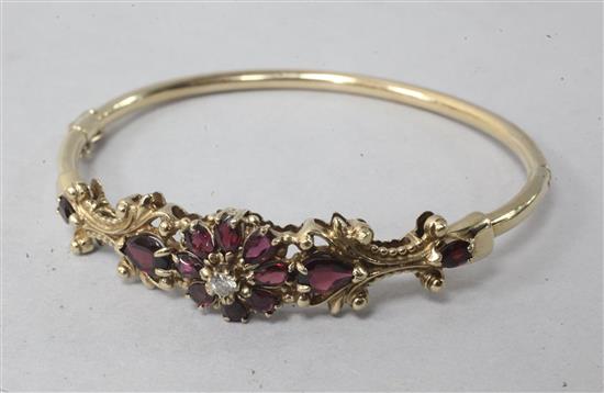A gold, diamond and garnet set hinged bangle.